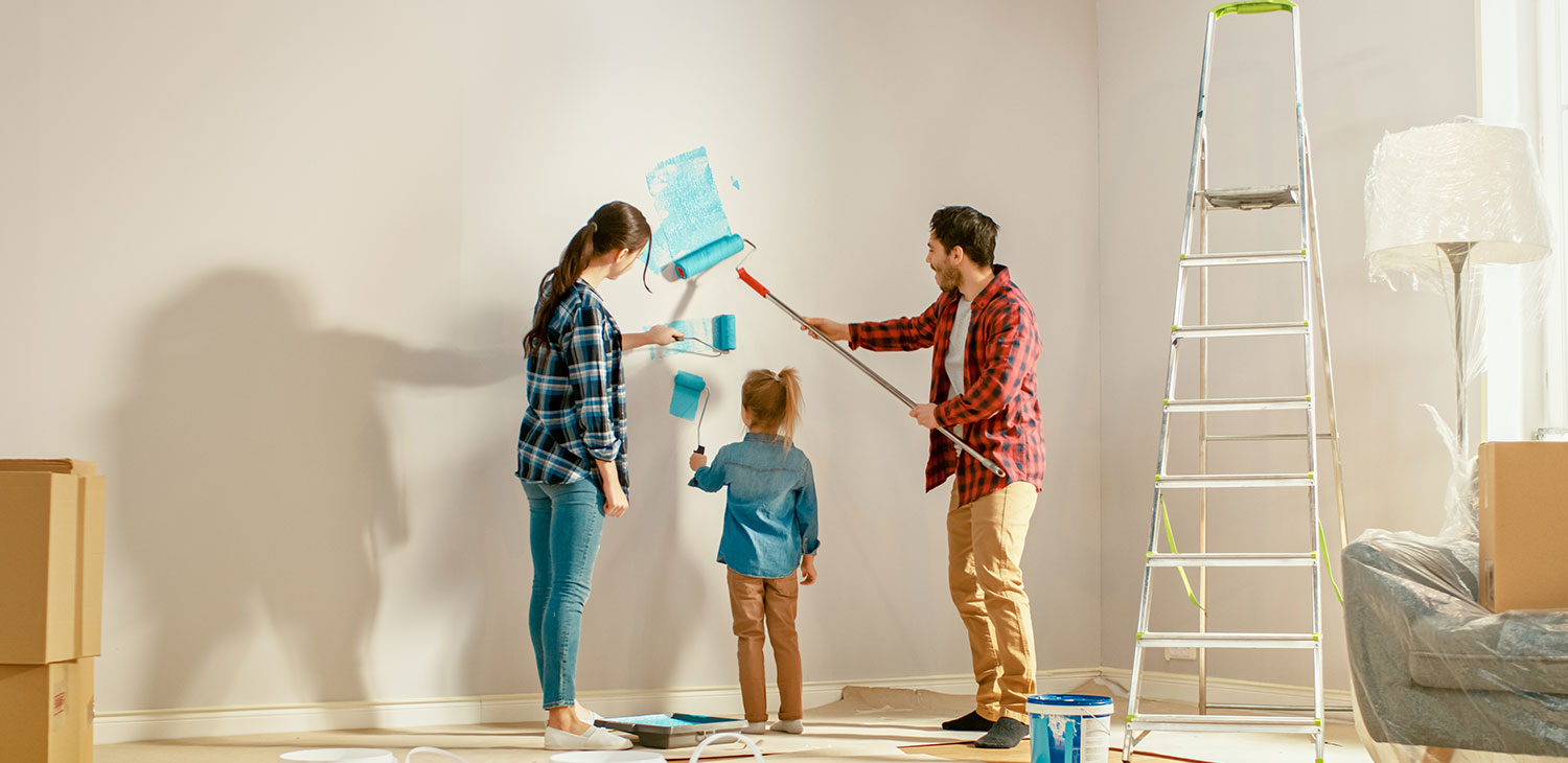 Young Family Showing Daughter How to Paint Walls